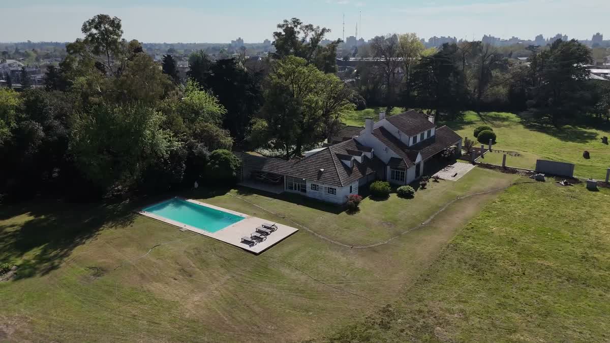 La casona histórica con techo de tejas y la pileta, vistas desde el drone